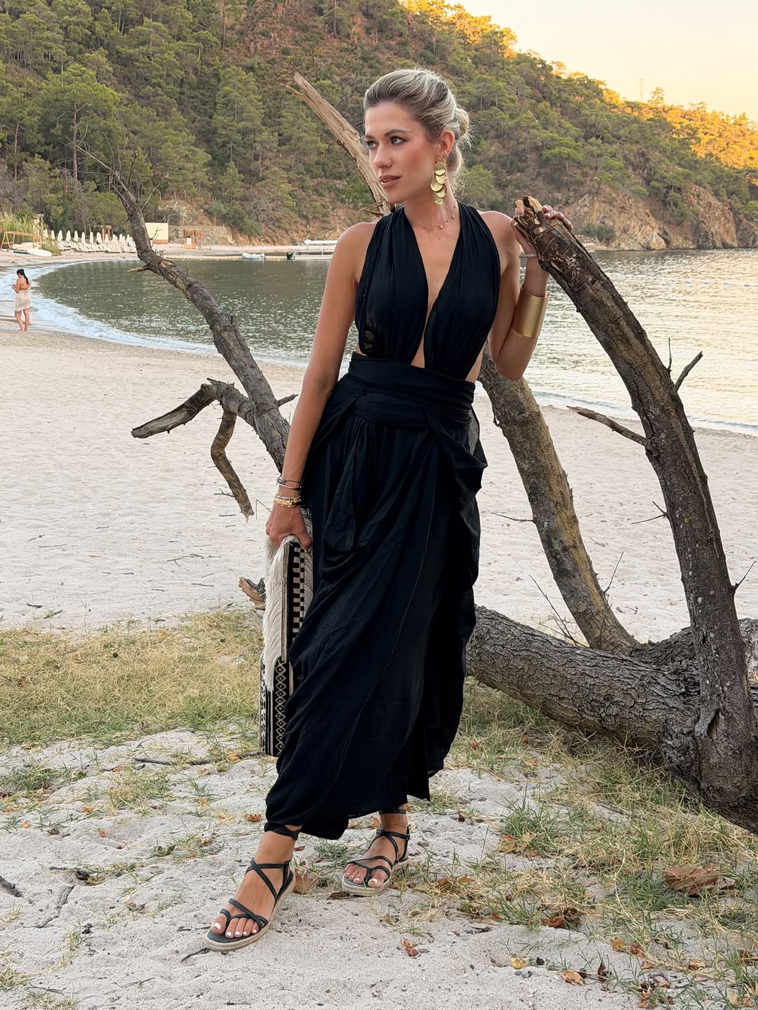Elegant black halter wrap dress styled with strappy sandals and gold jewelry for